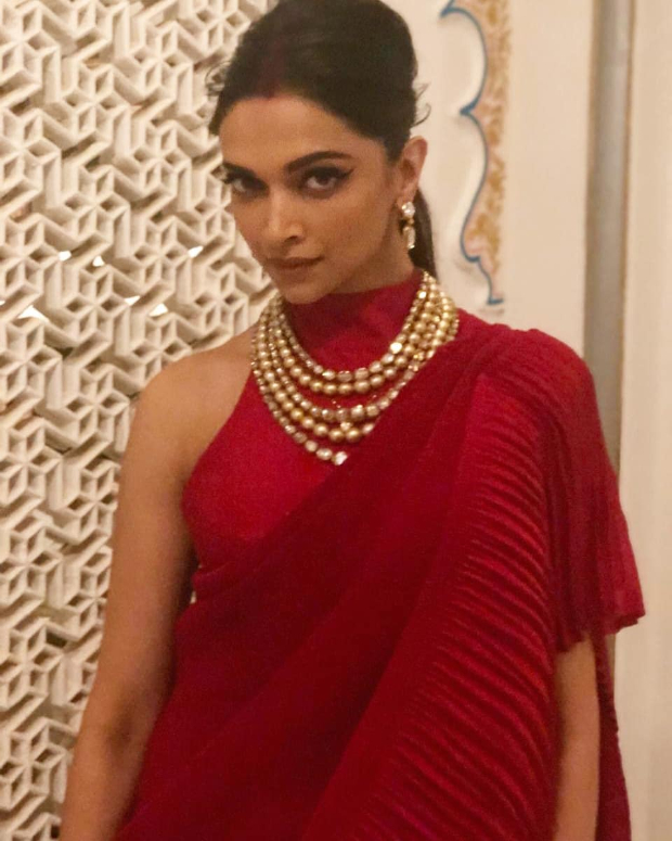Deepika Padukone – her unmistakable elegance and ethereal charm is always a delight! She infuses life in ethnic ensembles and western ones with her lithe and svelte frame in tow and that hard-to-miss dimpled smile. The pre-wedding festivities, sangeet ceremony of Isha Ambani and Anand Piramal saw the new bride Deepika Padukone stun in a red ensemble from Faabiiana. Styled by Shaleena Nathani, Deepika pulled off the red ensemble from designers Kusum & Karishma Luharuwala’s label. Also Read: Sun, Sand and Bikini – Summer has officially begun for Deepika Padukone (View Pictures) The neo-Indian saree featured a pleated long train drape teamed with a halter neck backless blouse. Deepika upped the look with a layered necklace, earrings and her traditional red wedding chura. Also Read: INSIDE VIDEOS: Newlyweds Deepika Padukone – Ranveer Singh get groovy with Aishwarya Rai Bachchan, Sidharth Malhotra, Karisma Kapoor at Isha Ambani – Anand Parimal bash With sindoor in her forehead, Deepika sported a messy low back ponytail, courtesy hairstylist Gabriel Georgiou. Her glowy makeup featured winged defined eyebrows, nude lips and lightly contoured cheekbones, courtesy makeup artist Priya Todarwal. Also Read: Deepika Padukone BEATS Priyanka Chopra to be the SEXIEST woman in Asia On the professional front, Deepika Padukone was last seen as Rani Padmavati in Sanjay Leela Bhansali’s Padmaavat.