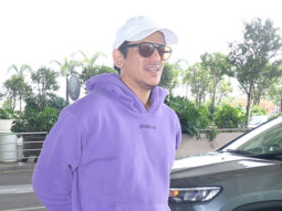 Vijay Varma smiles for paps in a purple hoodie and a cap at the airport