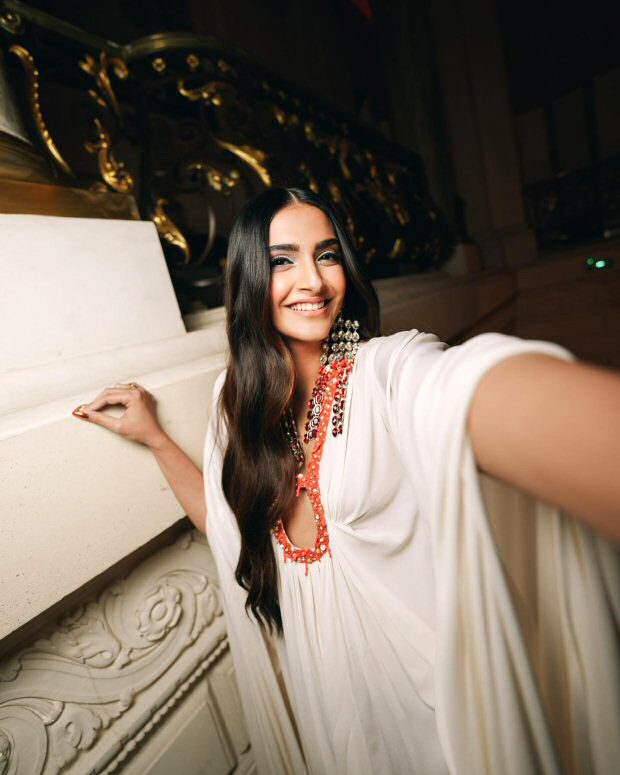 Sonam Kapoor radiates elegance in a flowy white dress, adorned with ombre and ruby-red dangler earrings