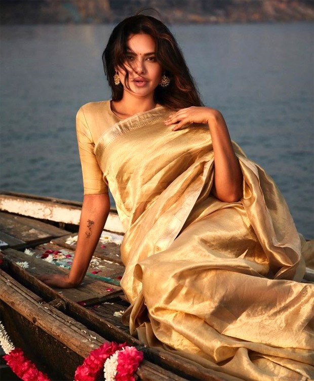 Esha Gupta radiates ethereal elegance in a golden saree against the backdrop of Benaras ghats