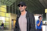 Arjun Rampal smiles as he poses for a picture with fans at the airport